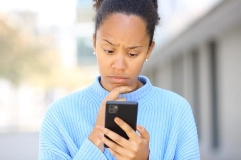 Worried black woman checking phone in the street